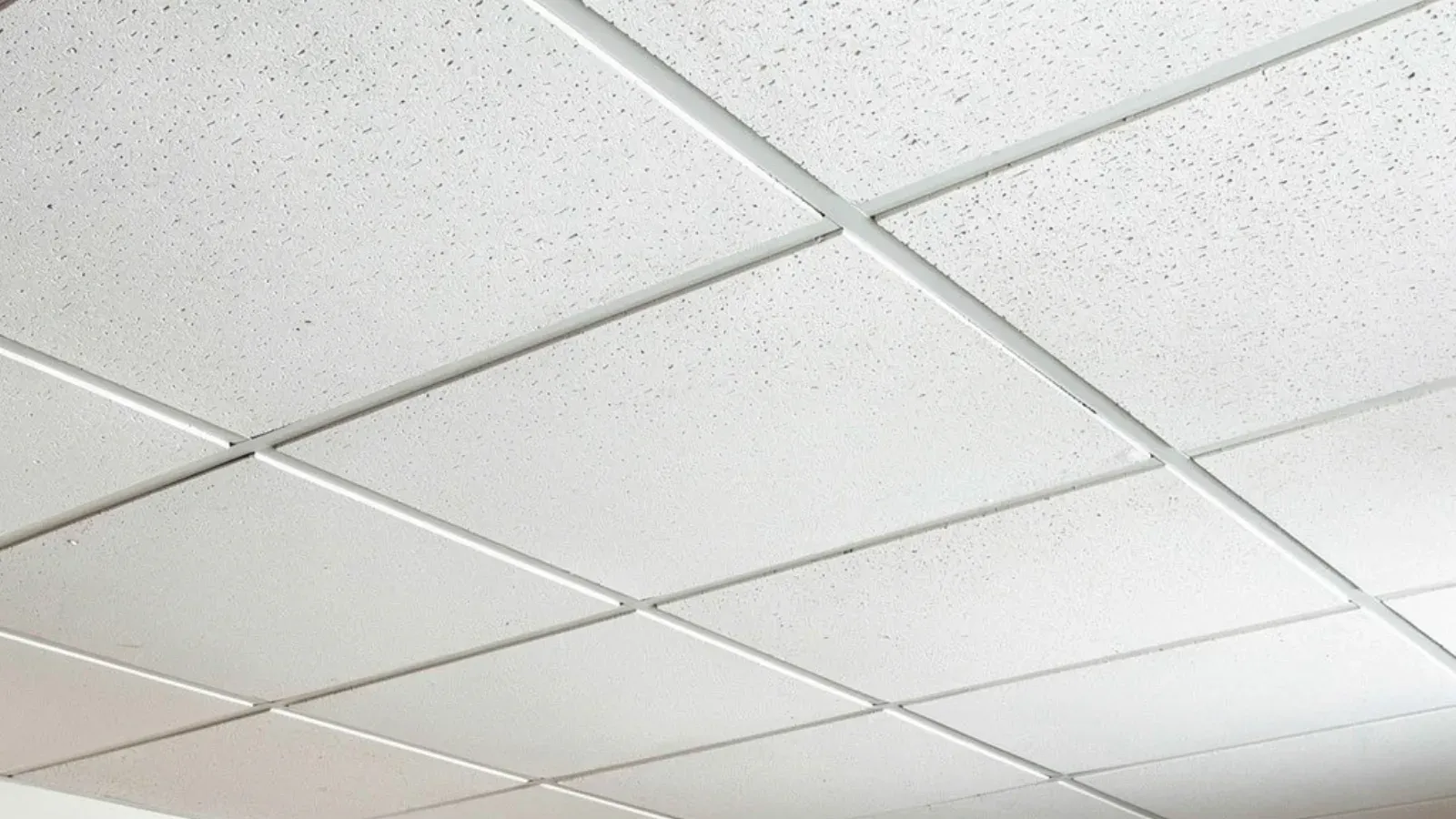 A suspended acoustic tile ceiling with every panel set into a white T-bar grid