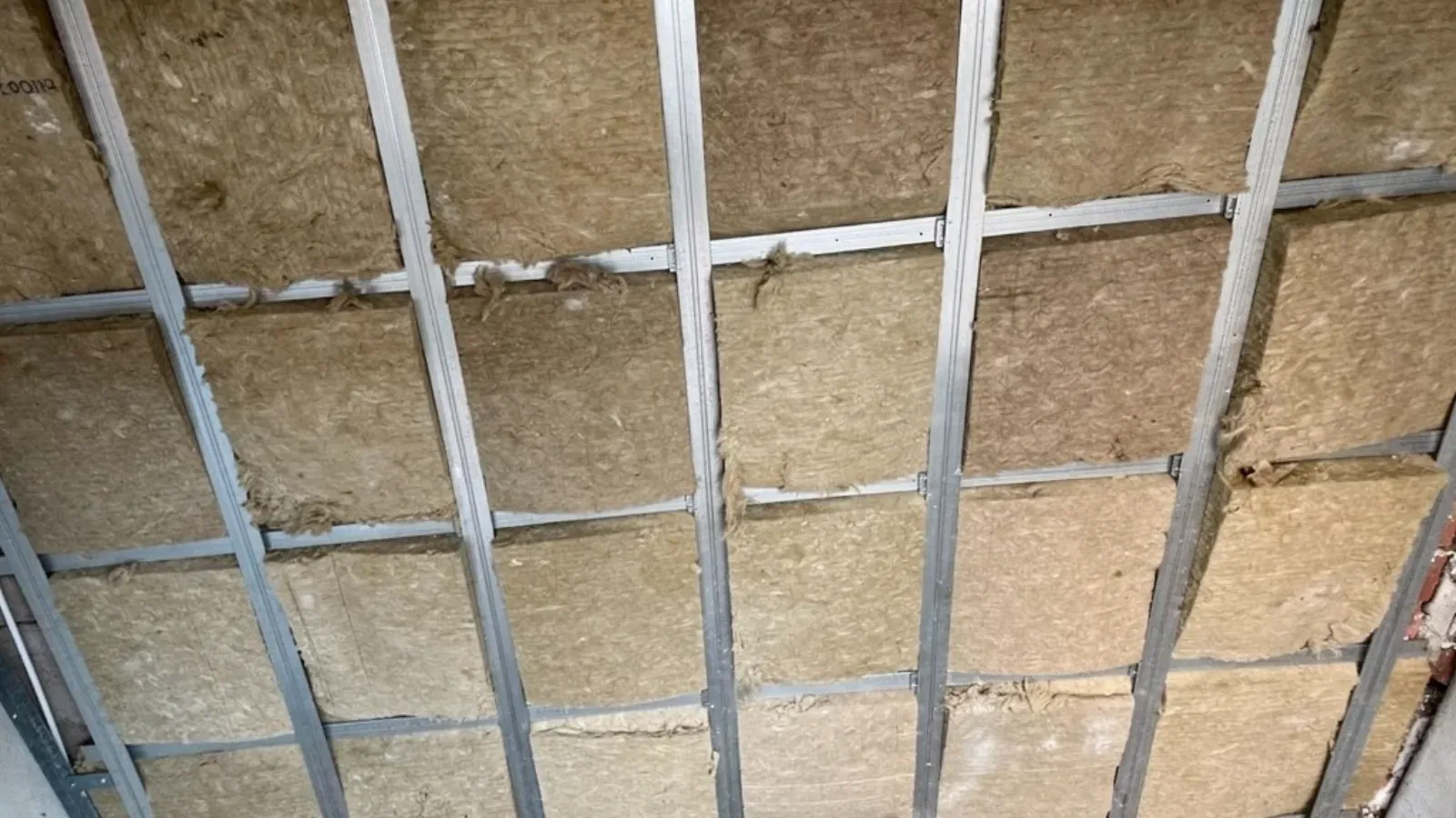 Ceiling with mineral wool insulation held between metal furring channels, before drywall is hung